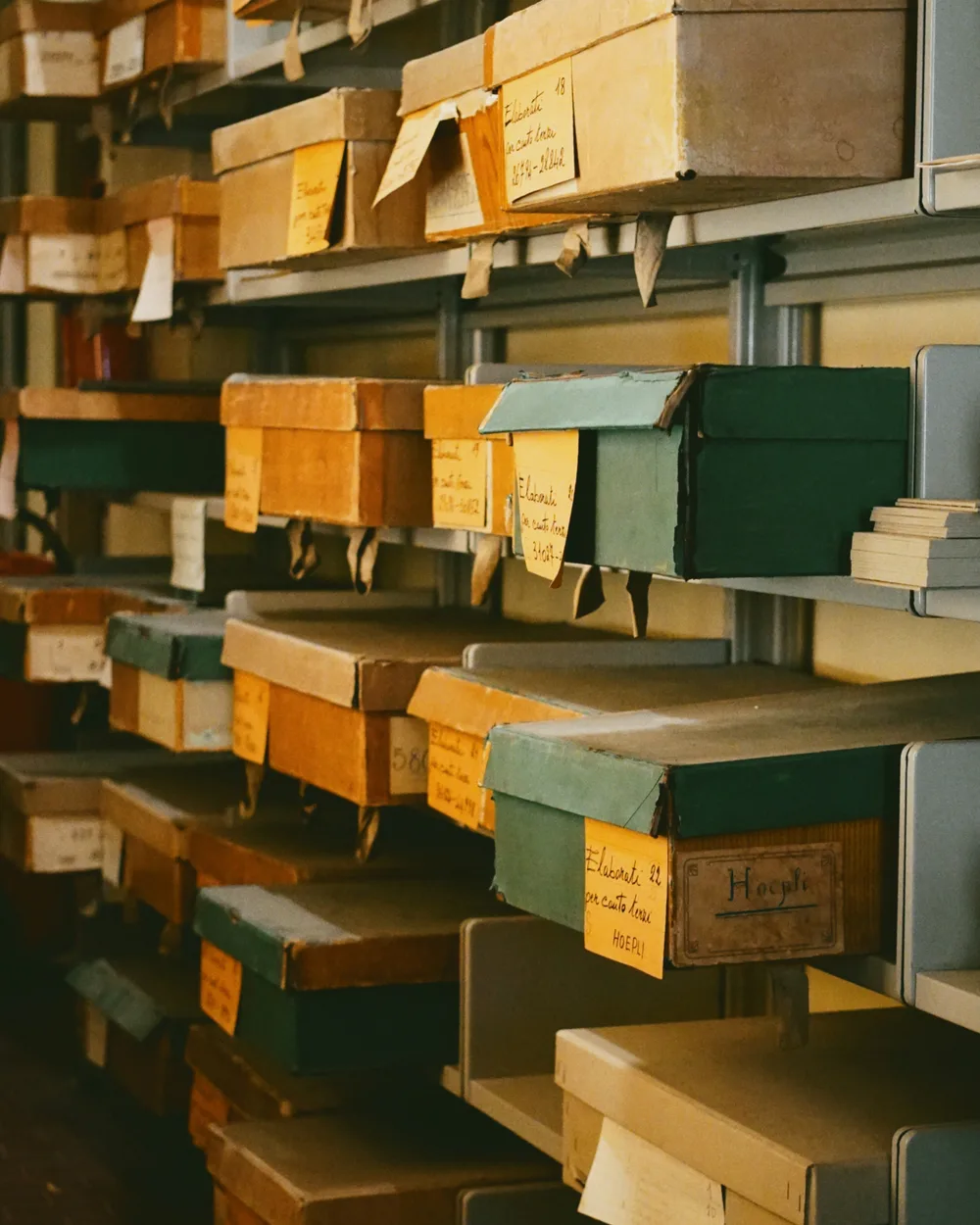 Shelves of worn archive boxes with handwritten paper labels